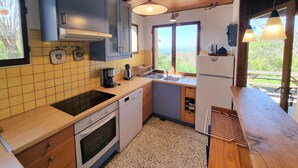 A compact kitchen with a wooden ceiling, a large window, and a sink.