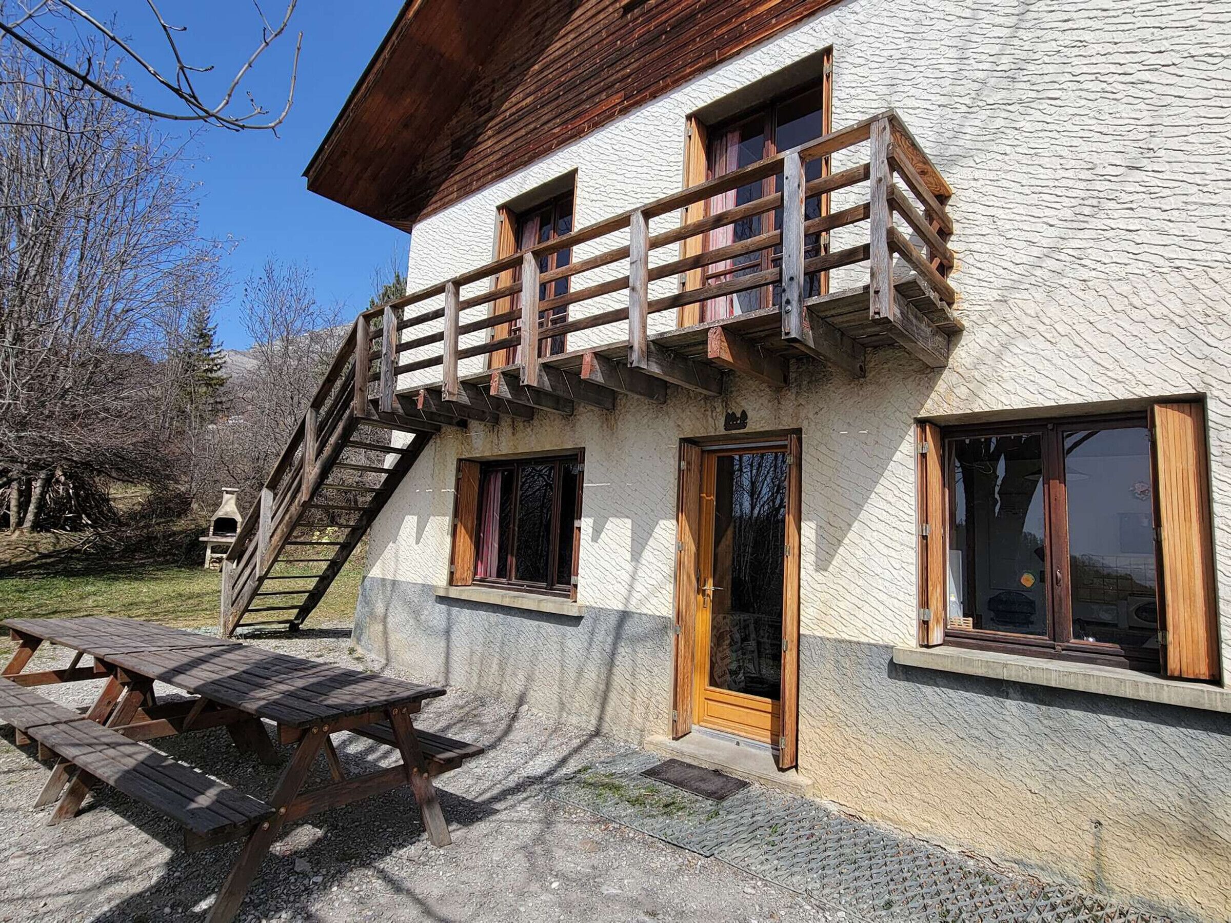 Een rustieke chalets met een houten balkon, een stenen gevel en een houten deur.