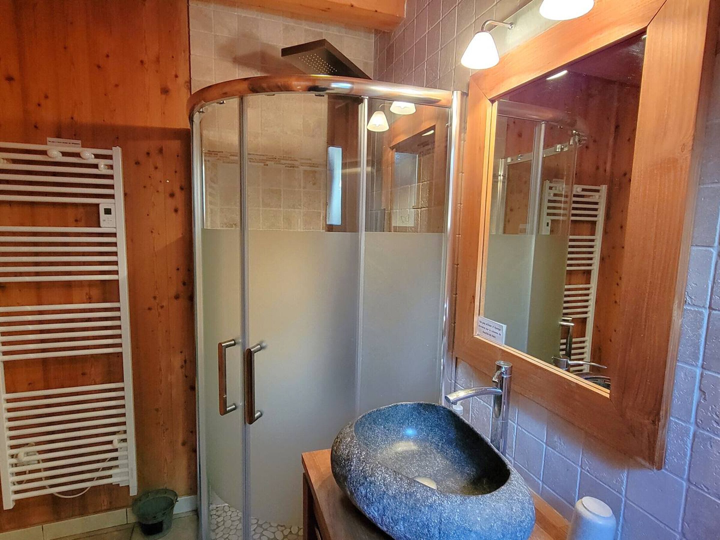 Ein modernes Badezimmer mit Duschkabine aus Glas, einem freistehenden Waschbecken und einem Holz-Waschtisch.