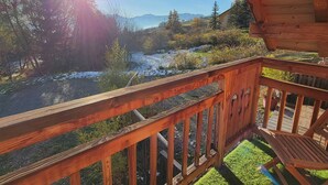 Une terrasse en bois offrant une vue sur un paysage enneigé et des montagnes au loin.