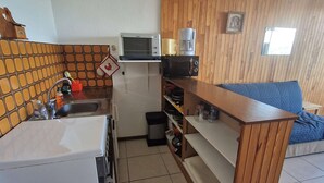 A compact kitchen with a sink, a microwave, and a coffee maker on a shelf.