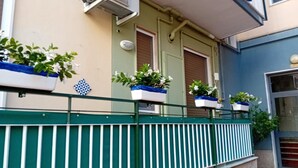 A building with a green railing, potted plants on the balcony, and a door with a window. - CdApartments - 2-Min Walk to the Beach & Town Center (Minori)