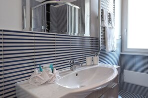 A bathroom with a large sink, striped tile backsplash, and a mirror.