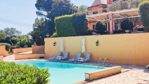Un espace piscine doté de chaises longues et d’une piscine à l’eau d’un bleu cristallin.