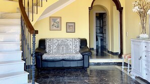 A staircase with a wooden handrail and black balusters, leading to a landing with a black leather sofa and a patterned throw. - CHALET WITH PISICINA AND VIEWS OF DREAM (Almuñécar)
