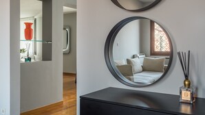 Een moderne kamer met een grote spiegel, een zwarte dressoir en een vaas met rietstengels.
