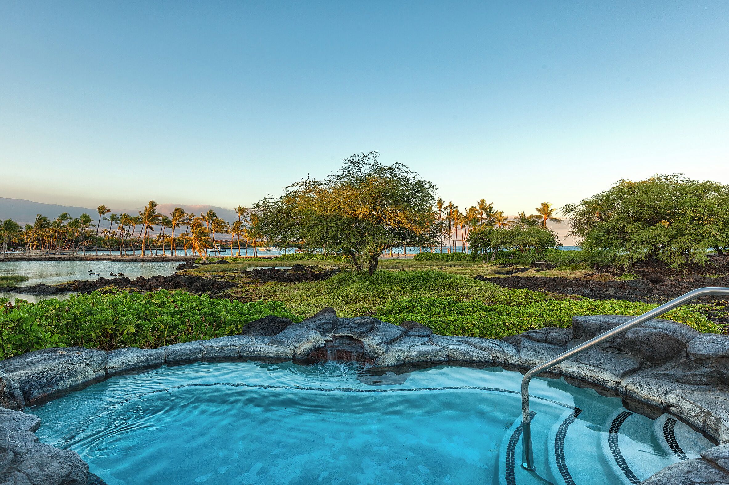 A pool area with a clear view of the surrounding landscape, including trees and a distant shoreline.