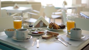 A breakfast tray with croissants, juice, and coffee in a bright dining area with white furniture. - Hotel Rio (Chajarí)