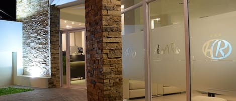 A modern hotel exterior with stone pillars, a glass entrance, and a logo on the glass wall.