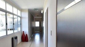 A hallway with large windows, a radiator, and red vases. - Hotel Rio (Chajarí)