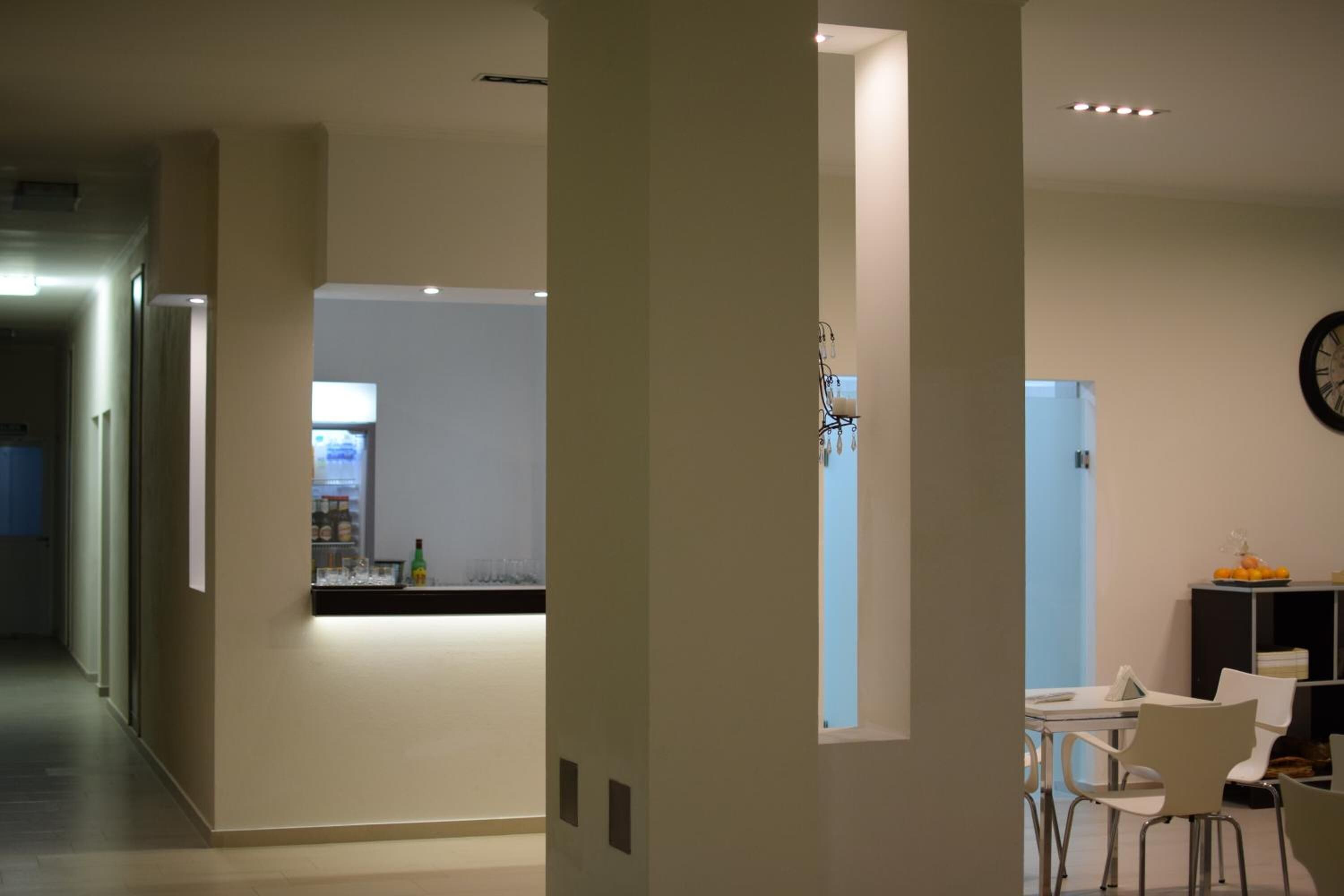 A modern interior with a kitchen area, dining space, and a visible clock on the wall.