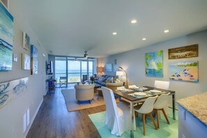 A spacious living area with a dining table, chairs, and a view of the ocean through large windows. - Bay Tree Bliss | Pool | Full Views of the Gulf! (Sarasota)