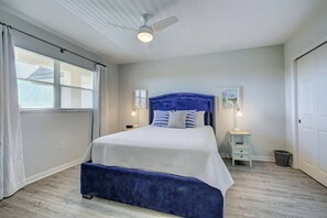 A bedroom with a bed, a ceiling fan, a nightstand, and a window with curtains.