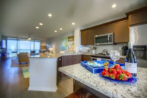 Una cocina moderna con encimeras de granito, una isla central y una botella de vino.