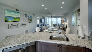 A modern kitchen with granite countertops, a built-in dishwasher, and a large window overlooking a balcony. - Private Beach Access | Ocean Views | Pool | Full Views of the Gulf of Mexico | Bay Tree Bliss (Sarasota)