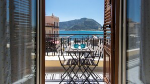 Un balcón con mesa y sillas, con vista a una piscina y un paisaje montañoso.