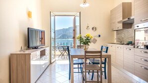 Una cocina moderna con comedor, televisor y vista al mar.
