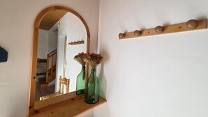 Ein Spiegel mit Holzrahmen, eine Holzablage mit zwei grünen Vasen und ein Holzmantelständer mit Haken.