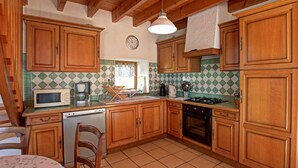 Cocina con armarios de madera, microondas, lavavajillas, estufa y fregadero.