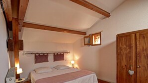 Un dormitorio con cama, lámpara de noche, armario de madera y una ventana pequeña.