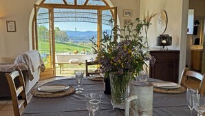 Mesa de comedor para cuatro con vistas al campo a través de un amplio ventanal de arco.