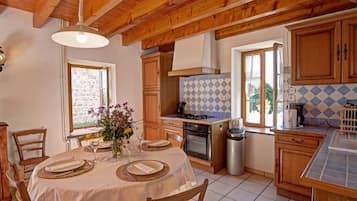 A kitchen with wooden beams, a dining table set for four, and a window with a view.