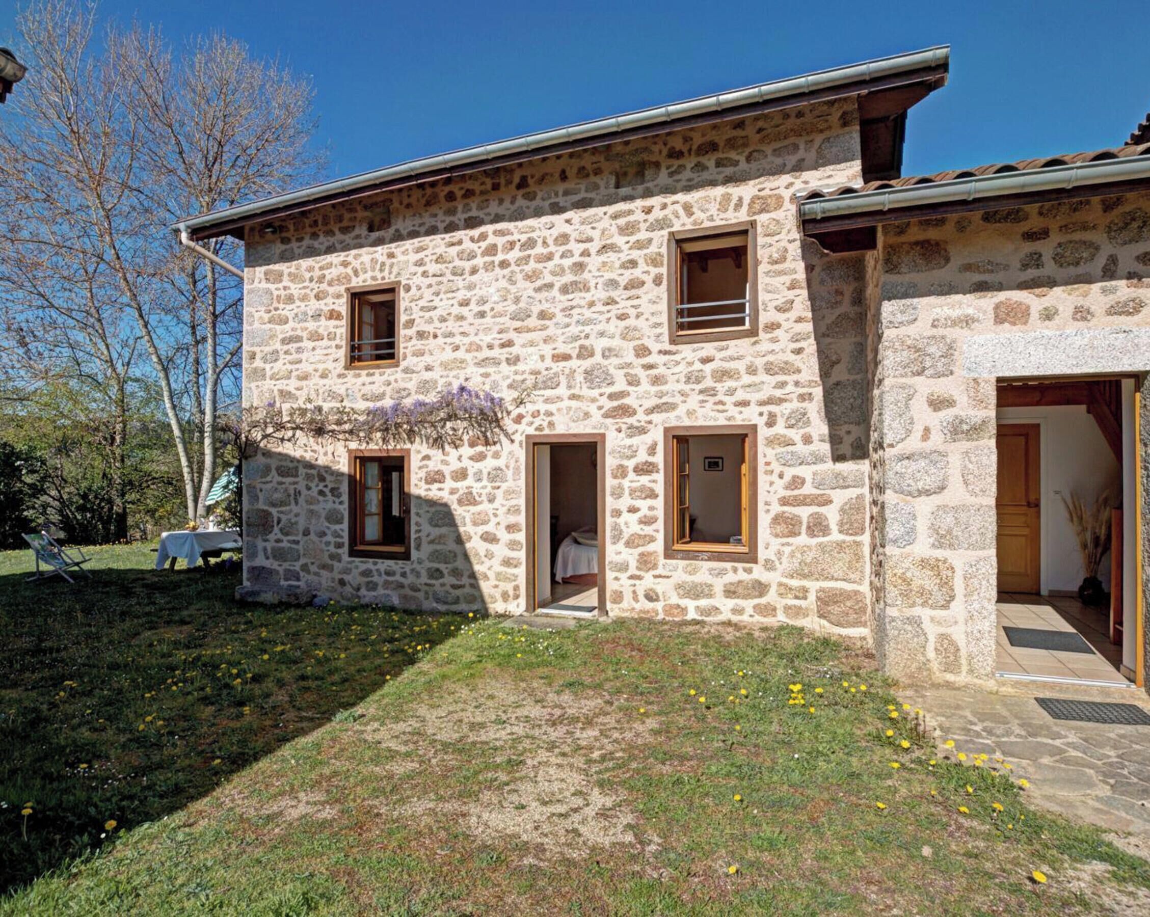 A stone building with multiple windows, a door, and a small garden area.