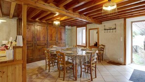 A dining area with a wooden table set for six, surrounded by chairs. There is a wooden door and a mirror on the wall. - Cozy cottage in natural park with pets allowed and modern comfort (Saint-Bonnet-le-Courreau)