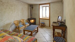 A cozy room with a fireplace, wicker furniture, and a window. - Cozy cottage in natural park with pets allowed and modern comfort (Saint-Bonnet-le-Courreau)