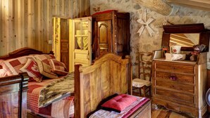 A rustic bedroom with wooden walls and a sloped ceiling. - Charming Cottage with Garden in Estivareilles (Estivareilles)