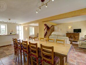 A spacious living area with a dining table surrounded by chairs, a staircase, a sofa, and a television. - Spacious house with heated pool, 4 bedrooms in Chalain-le-Comtal (Chalain-le-Comtal)