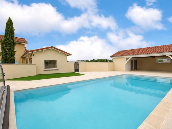 A swimming pool with a clear blue sky and a few clouds.