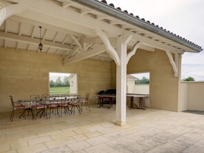 Een buitenpatio met een overdekte zithoek, een tafel en stoelen.