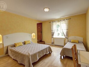 A room with two beds, wooden floors, and a window with curtains. - Spacious house with heated pool, 4 bedrooms in Chalain-le-Comtal (Chalain-le-Comtal)