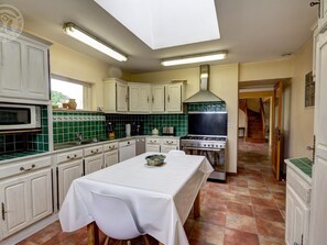 A kitchen with white cabinets, a stove, a microwave, and a table set for dining.
