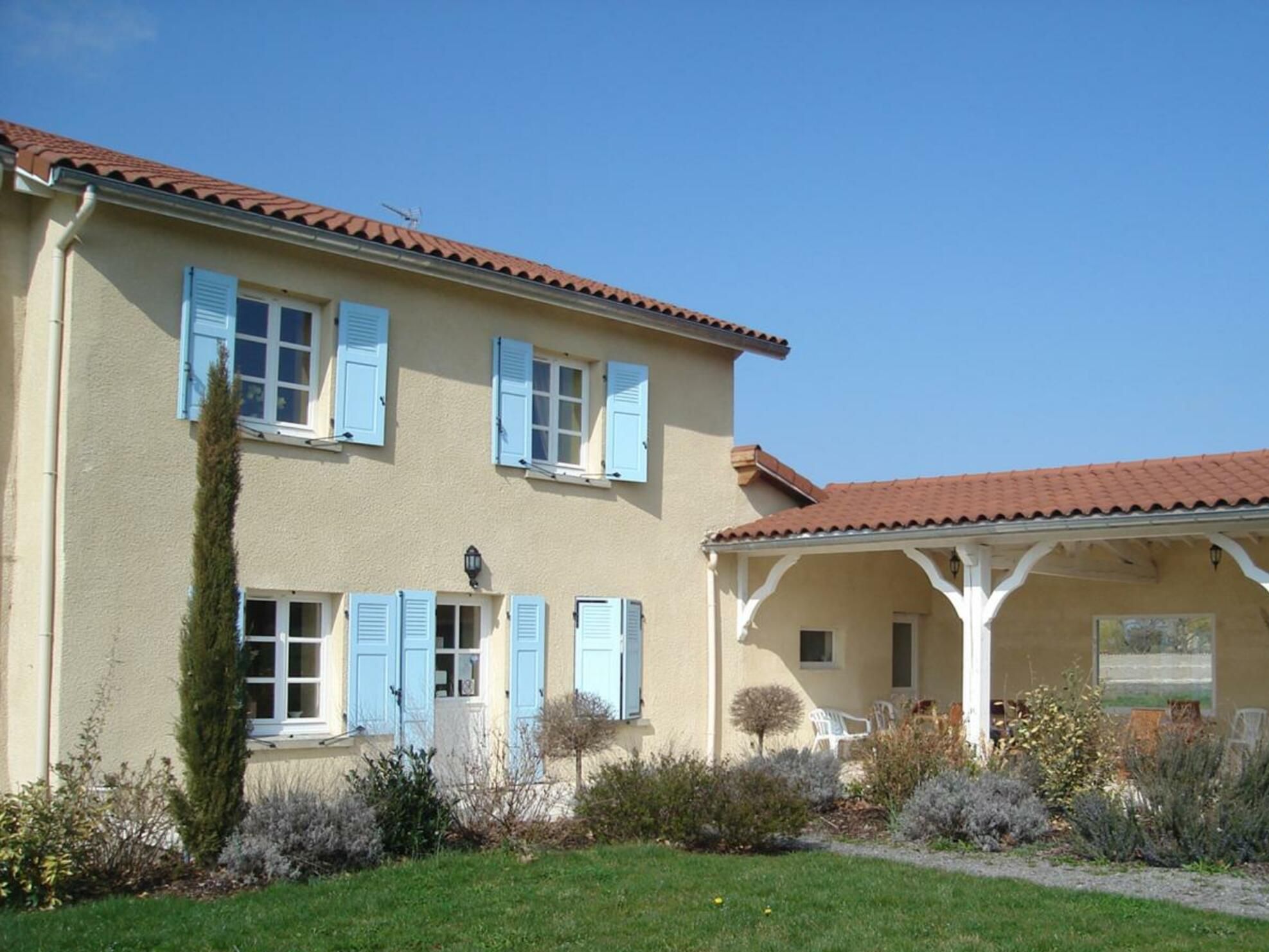 A two-story building with a tiled roof and blue shutters.