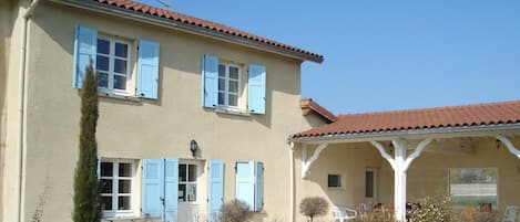 A two-story building with a tiled roof and blue shutters.