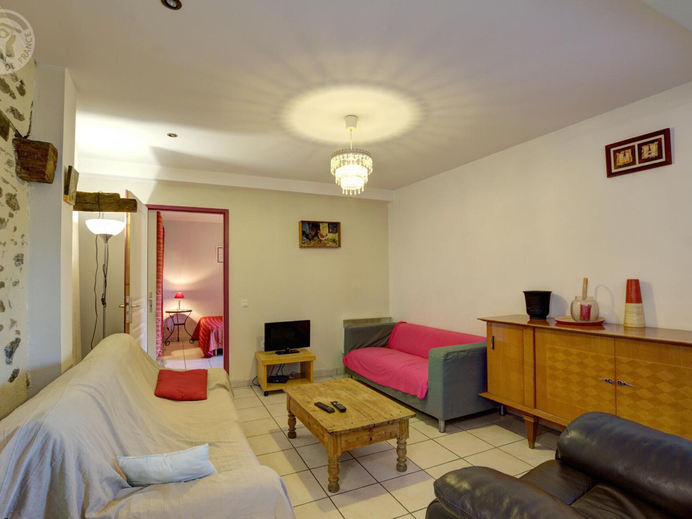 Una sala de estar con un sofá, una mesa de centro, un televisor y un mueble aparador.