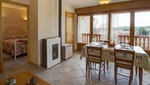 Een gezellige kamer met een bed, een open haard, een eettafel gedekt voor twee personen en een balkon met uitzicht.