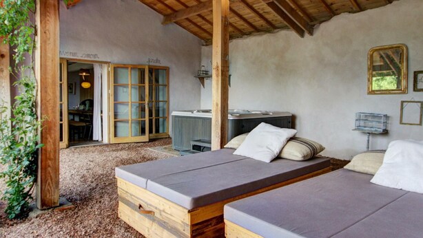 A rustic wooden room with a bed, a small table, and a hanging light fixture.