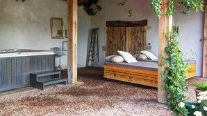 A rustic room with a wooden bed, a small desk, and a ladder.