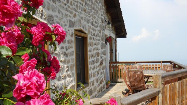 Un bâtiment en pierre doté d’une terrasse en bois, d’une porte et d’une fenêtre.