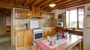 Une cuisine rustique avec des meubles en bois, un îlot central et une vue sur l’extérieur grâce à une grande fenêtre.