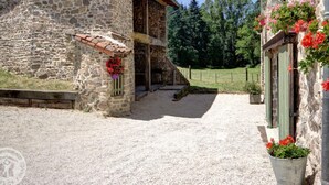 Un edificio de piedra con un camino de grava, una puerta de madera y un pequeño porche con techo de tejas.