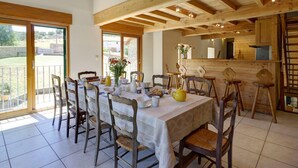 Un comedor con una mesa dispuesta para seis personas, sillas de madera y vistas al exterior a través de grandes puertas corredizas de vidrio.