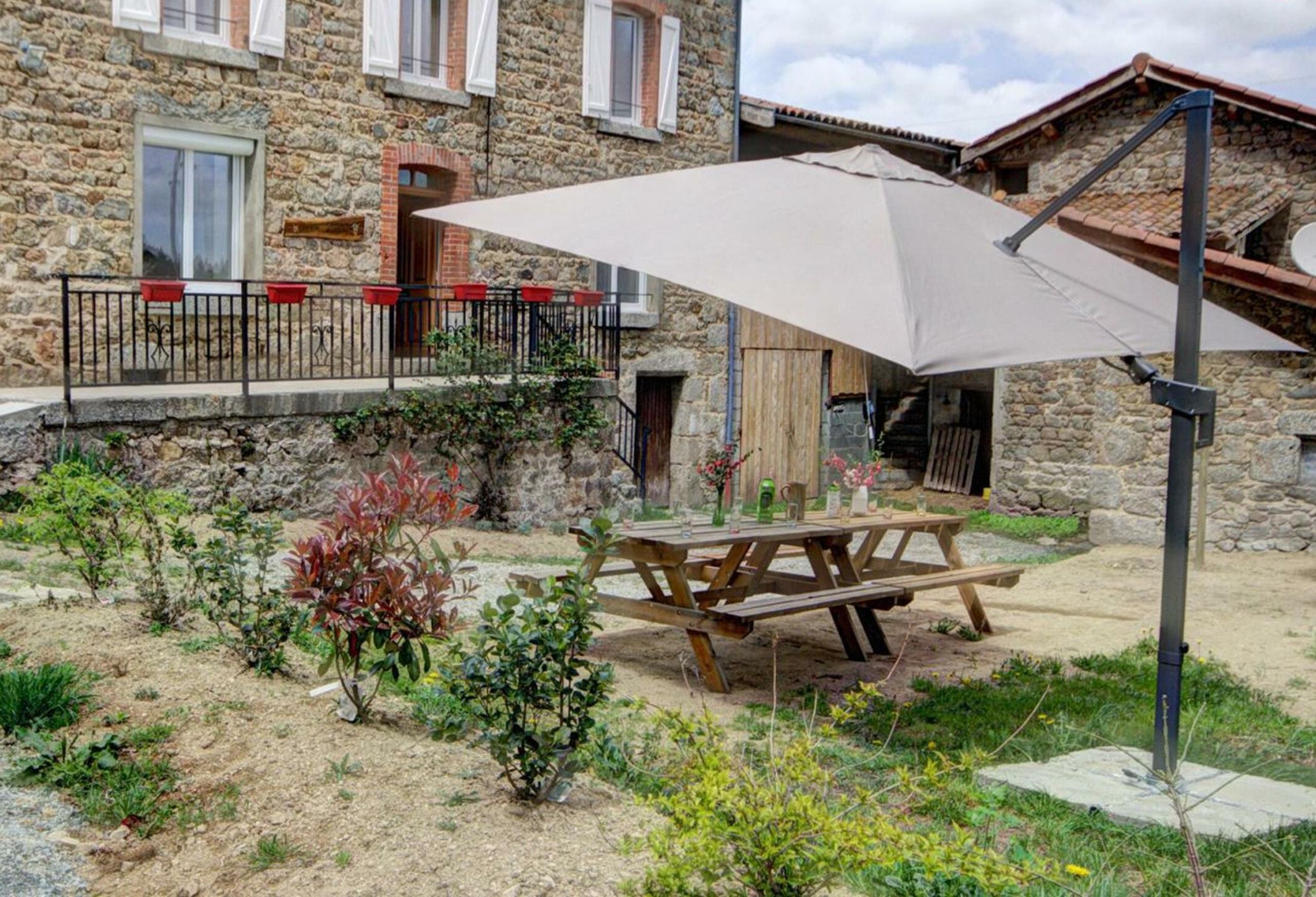 A stone building with a wooden balcony and a picnic table under a large umbrella.