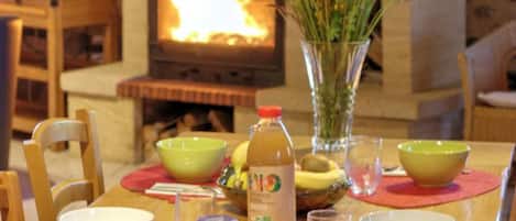 A dining table with a vase of flowers, bowls, and a bottle of juice.