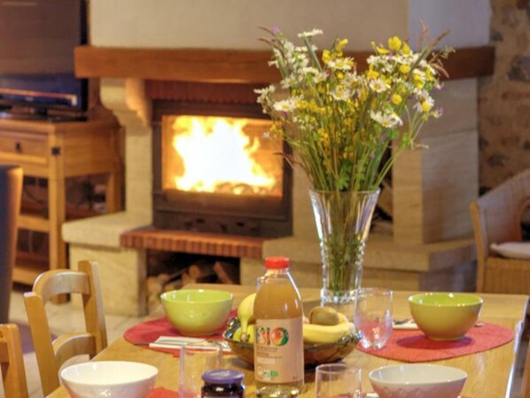 A dining table with a vase of flowers, bowls, and a bottle of juice.