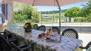 Un'area pranzo all'aperto con un tavolo apparecchiato per la colazione, comprendente una pagnotta, una bottiglia e delle tazze.