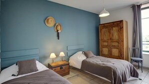 Een slaapkamer met twee bedden, een houten garderobe en een raam met gordijnen.